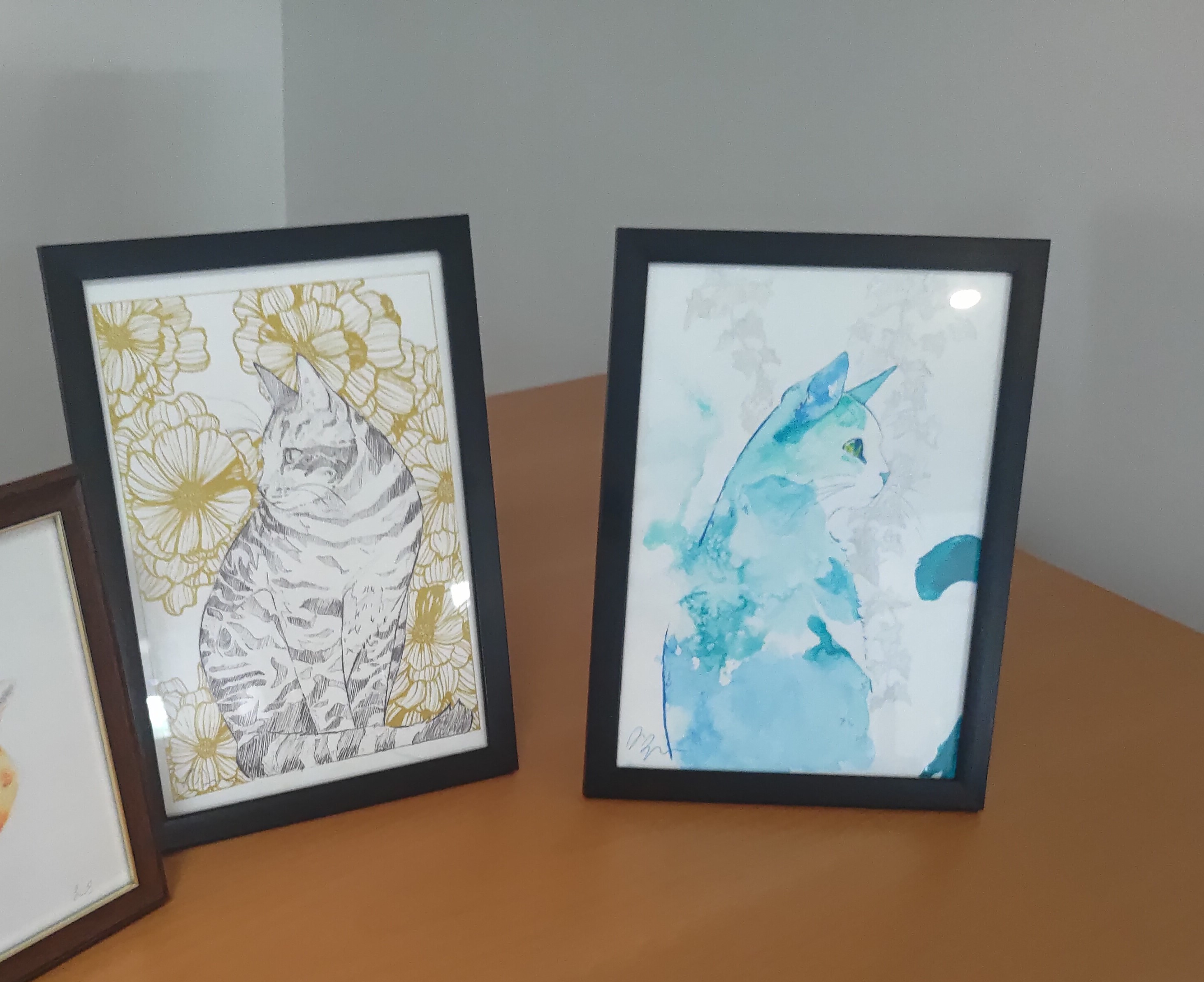 Two cat paintings framed